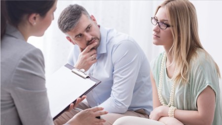 Image of two people talking with a woman holding a clip board.